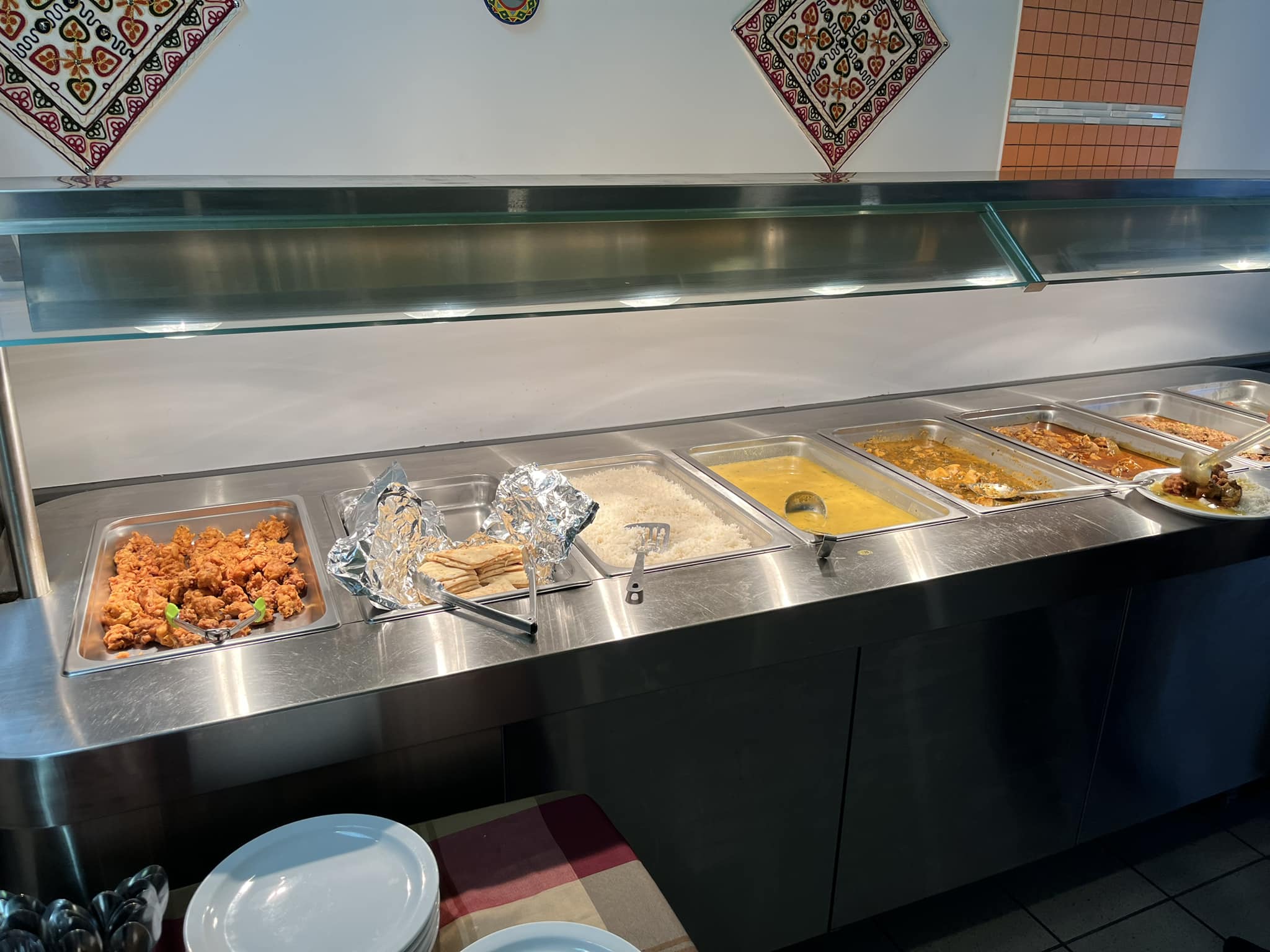 Stainless steel steam table filled with pans of curries and rice