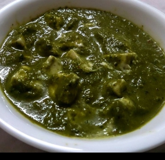 Palak paneer, spinach and cheese curry, in a white bowl