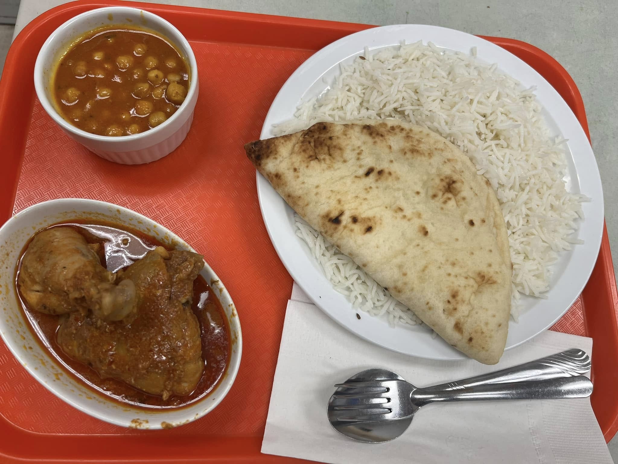 Chicken curry, chana, basmati rice and naan served on a tray at Desi Meal