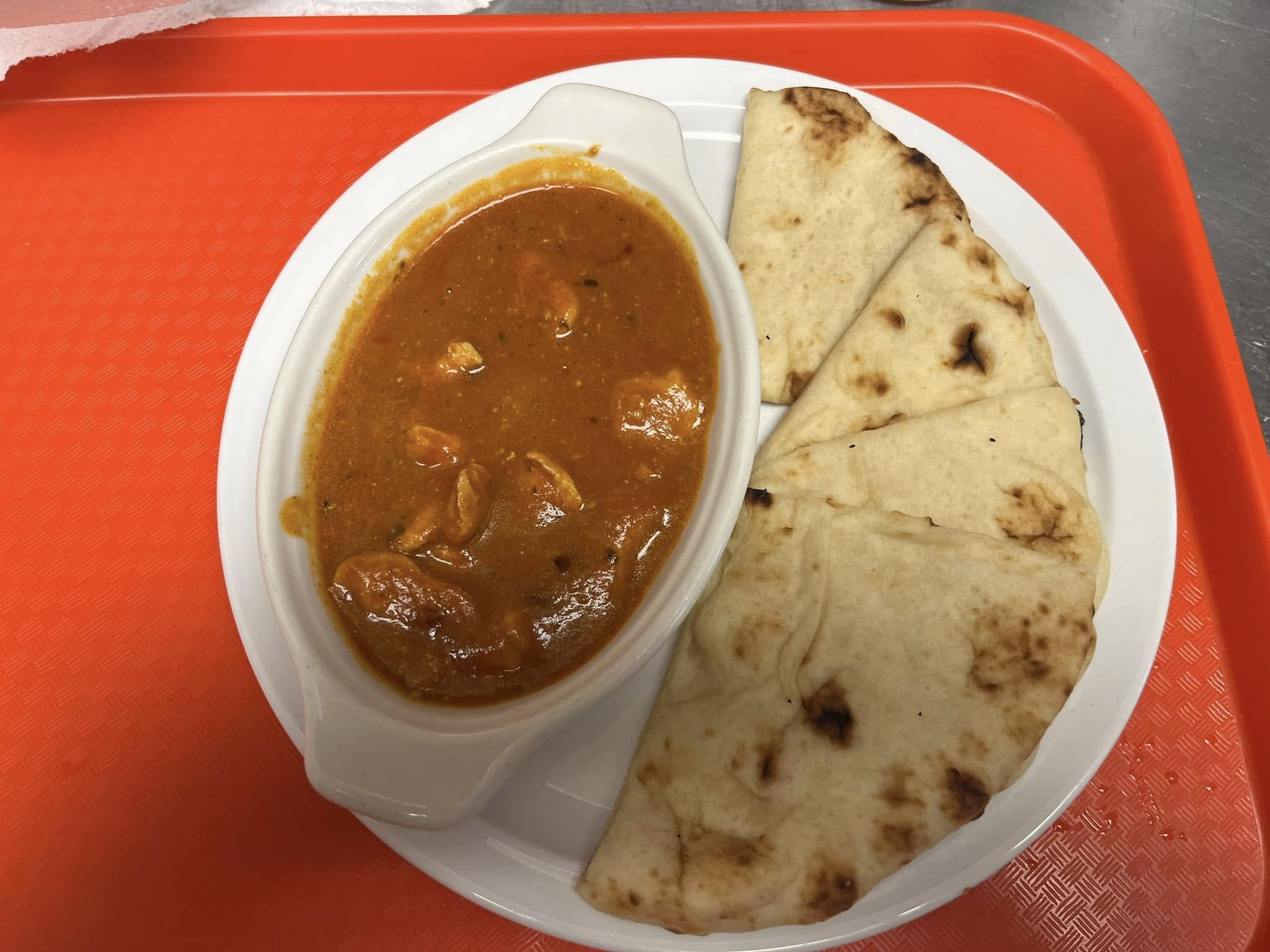 Chicken curry served with folded fresh naan on a plate at Desi Meal